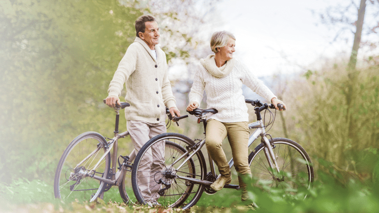 two aged couple resting on their bikes and talking