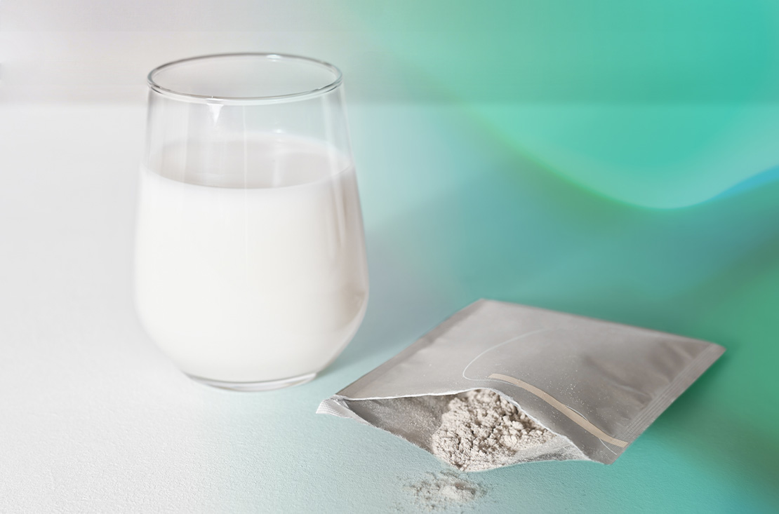 A glass of milk and a sachet of supplement